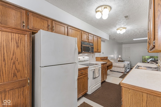 kitchen featuring a textured ceiling, white appliances, and sink