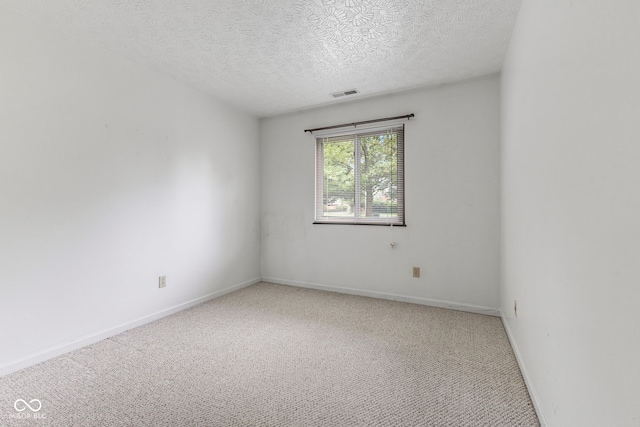 empty room featuring a textured ceiling and light colored carpet