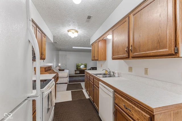 kitchen with a textured ceiling, white appliances, and sink