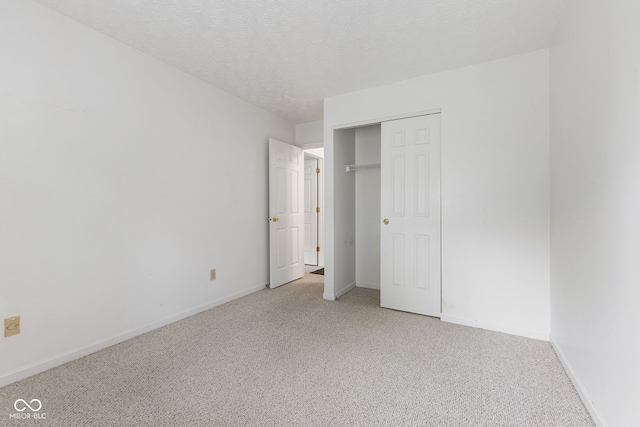 unfurnished bedroom featuring light carpet, a closet, and a textured ceiling