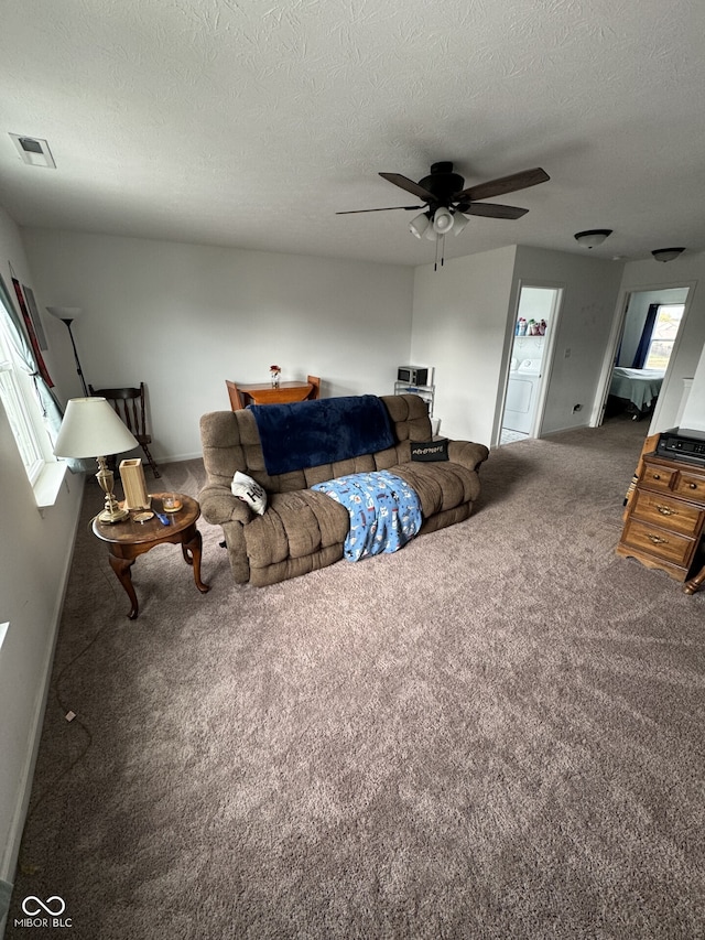 living room with ceiling fan, a textured ceiling, and dark carpet