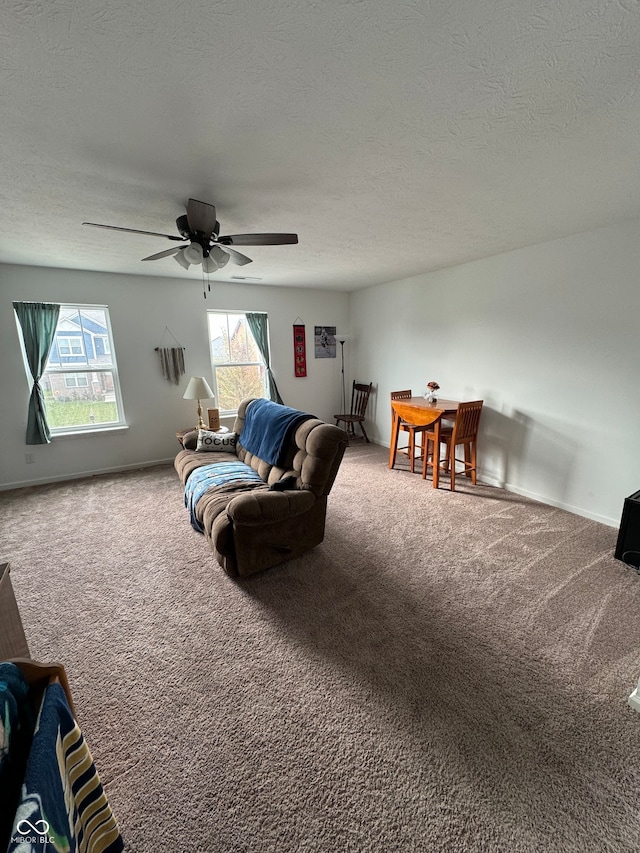 carpeted living room with ceiling fan and a textured ceiling