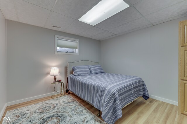 bedroom featuring light hardwood / wood-style floors and a paneled ceiling