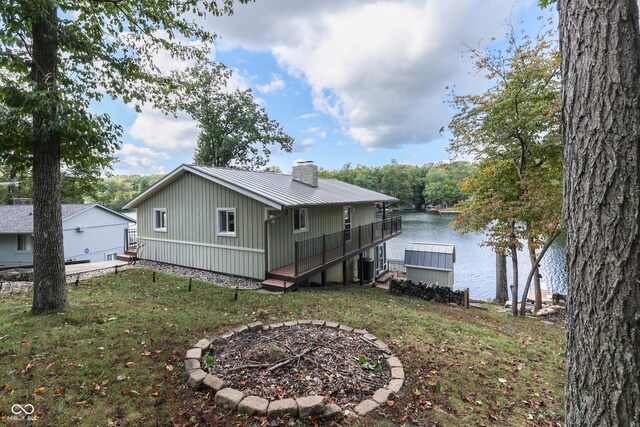 rear view of house featuring a yard, a fire pit, and a deck with water view