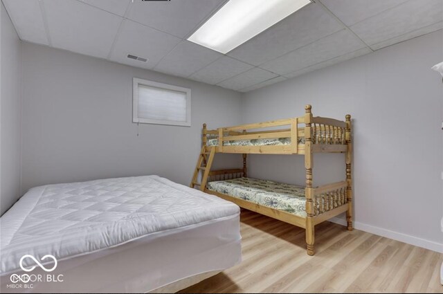 bedroom with a paneled ceiling and hardwood / wood-style flooring