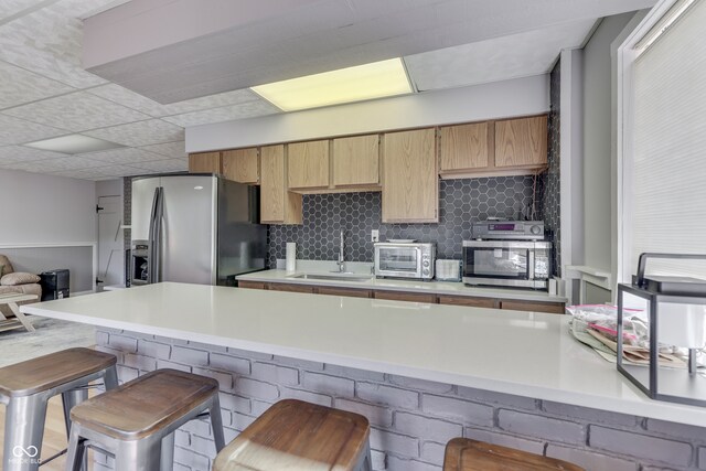 kitchen featuring appliances with stainless steel finishes, a breakfast bar, backsplash, kitchen peninsula, and sink