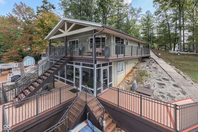 rear view of house featuring a storage shed, a wooden deck, and a patio