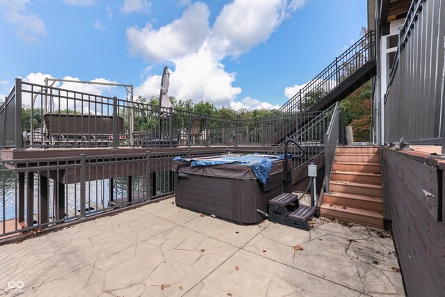 view of patio / terrace featuring a hot tub and a water view