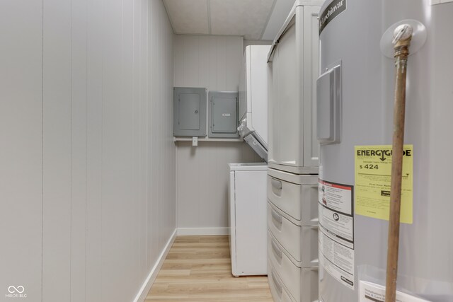 laundry area with light hardwood / wood-style floors, stacked washer / drying machine, electric panel, wooden walls, and water heater