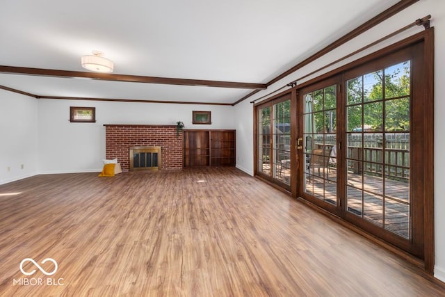 unfurnished living room featuring wood-type flooring, a fireplace, and crown molding