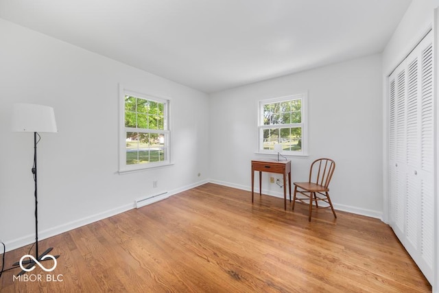 bedroom featuring a baseboard radiator, light hardwood / wood-style flooring, and a closet