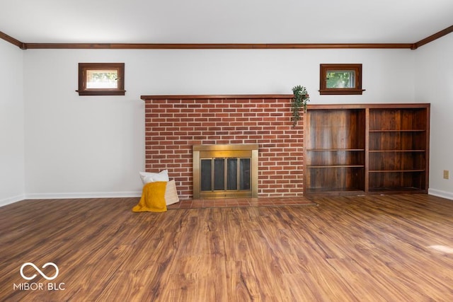 unfurnished living room with a brick fireplace, wood-type flooring, and ornamental molding