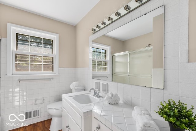 bathroom featuring tile walls, vanity, walk in shower, wood-type flooring, and toilet