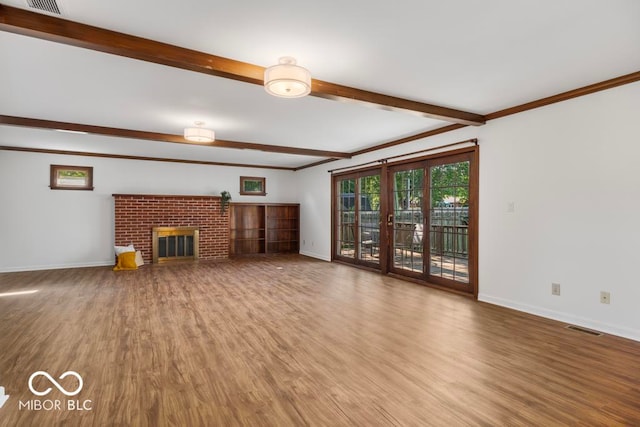 unfurnished living room featuring a brick fireplace, beam ceiling, and hardwood / wood-style floors