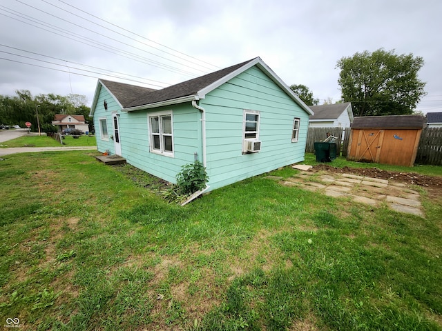 view of side of home with an outbuilding, a storage unit, a lawn, fence, and cooling unit