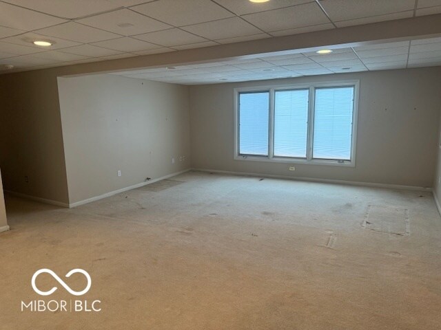 unfurnished room featuring light carpet and a paneled ceiling