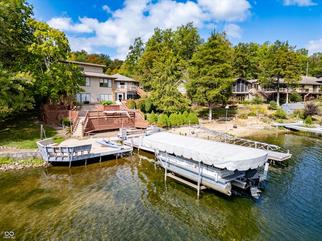 dock featuring a water view, boat lift, stairway, and view of wooded area