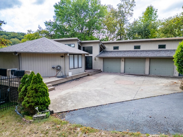 view of front of house with concrete driveway, an attached garage, and a shingled roof