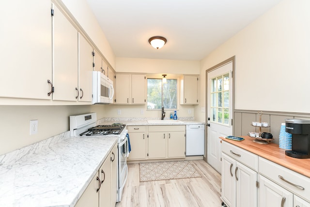 kitchen with light wood-type flooring, white appliances, sink, and white cabinets