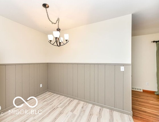 unfurnished room with a chandelier and light hardwood / wood-style flooring