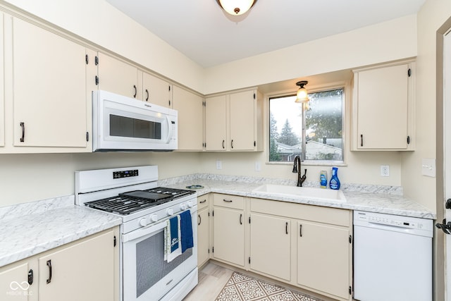 kitchen featuring white appliances, sink, and cream cabinets