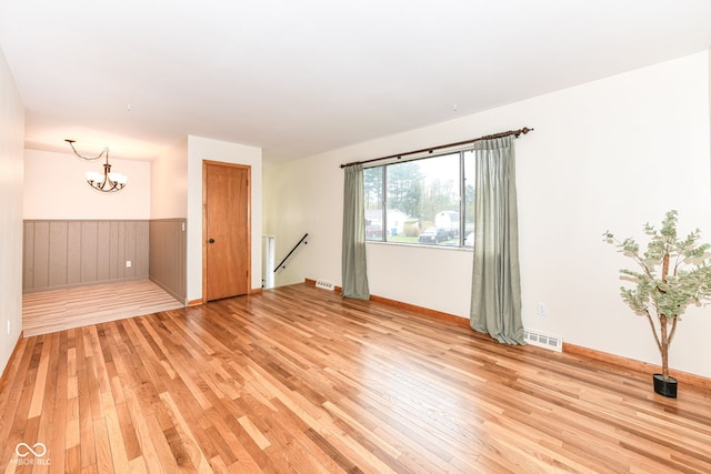 spare room featuring light wood-type flooring and an inviting chandelier