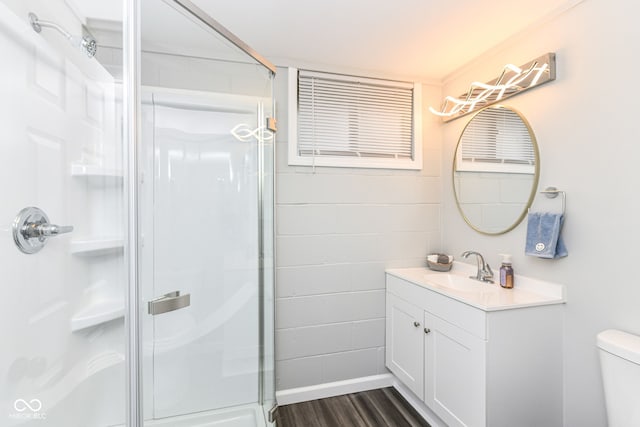 bathroom featuring hardwood / wood-style flooring, a shower with shower door, vanity, and toilet