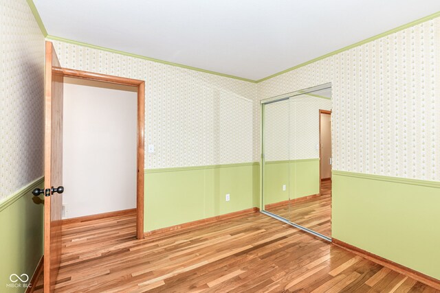 unfurnished bedroom with a closet, light wood-type flooring, and crown molding