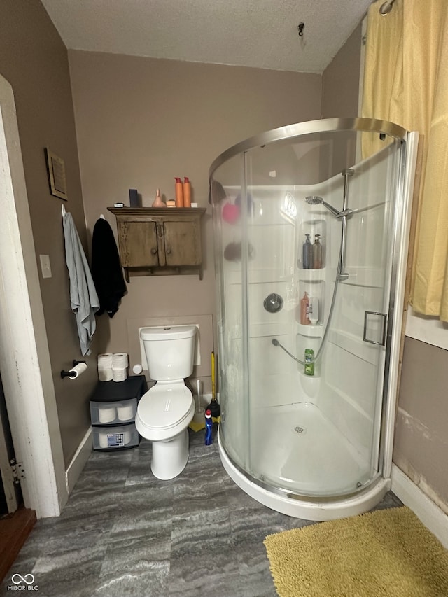 bathroom featuring a textured ceiling, toilet, and an enclosed shower