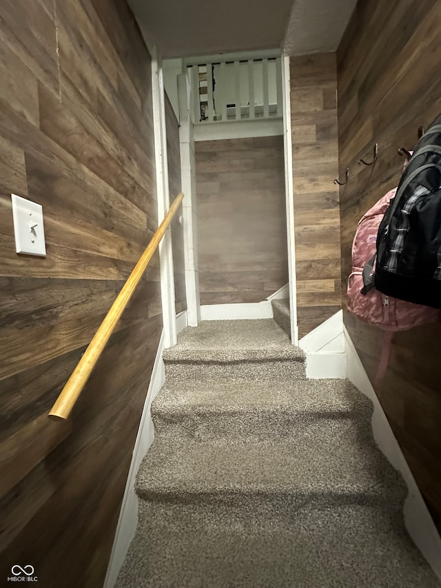 stairway featuring wood walls