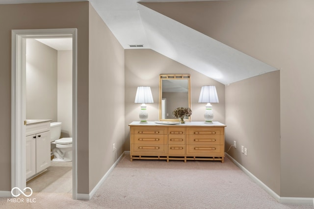 bedroom featuring vaulted ceiling, light carpet, and ensuite bathroom