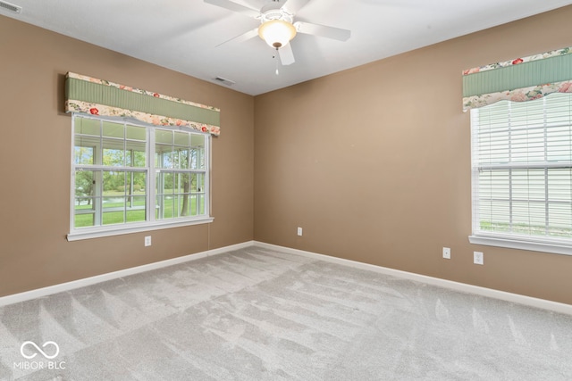 carpeted spare room featuring ceiling fan and a wealth of natural light