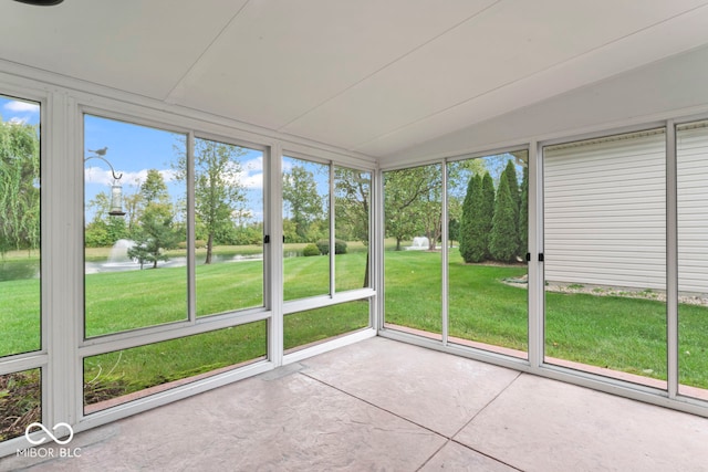 unfurnished sunroom with vaulted ceiling, a water view, and a healthy amount of sunlight