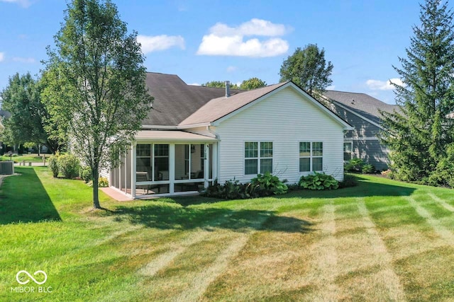 back of property with a sunroom and a lawn