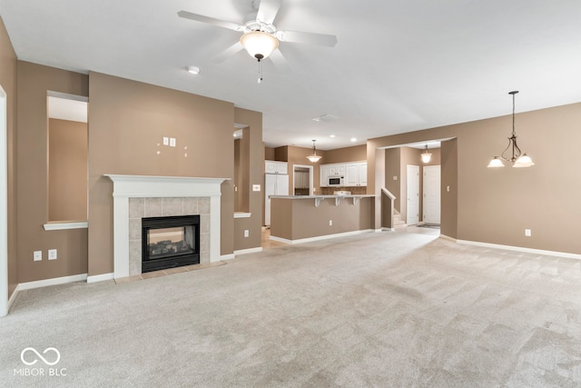 unfurnished living room with ceiling fan, a fireplace, and light carpet