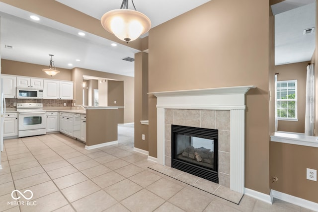 kitchen featuring a tile fireplace, pendant lighting, white cabinets, and white appliances