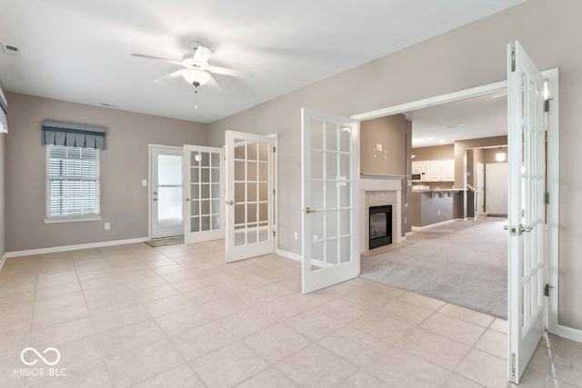 unfurnished room with ceiling fan, light carpet, a fireplace, and french doors