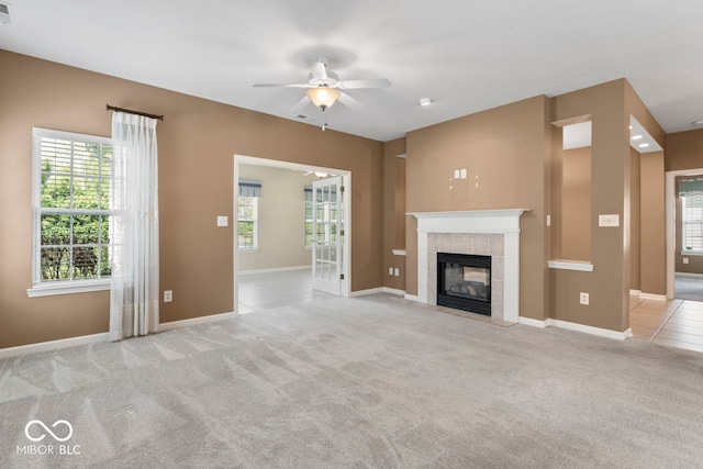 unfurnished living room with a tile fireplace, light carpet, and ceiling fan