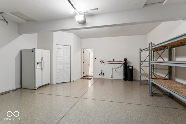 garage featuring a garage door opener and white fridge with ice dispenser