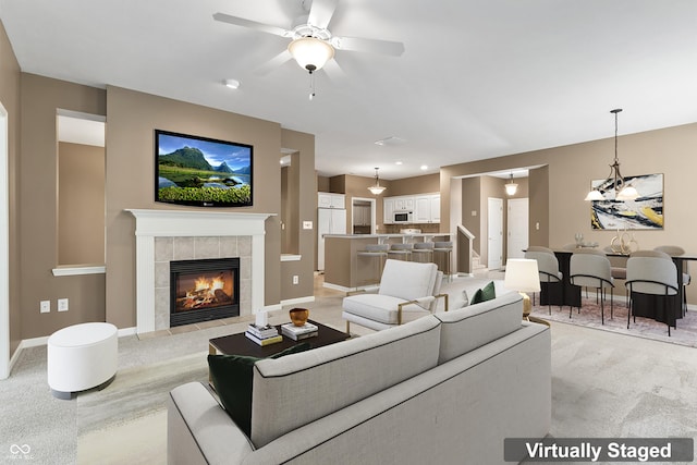 carpeted living room featuring a tile fireplace and ceiling fan