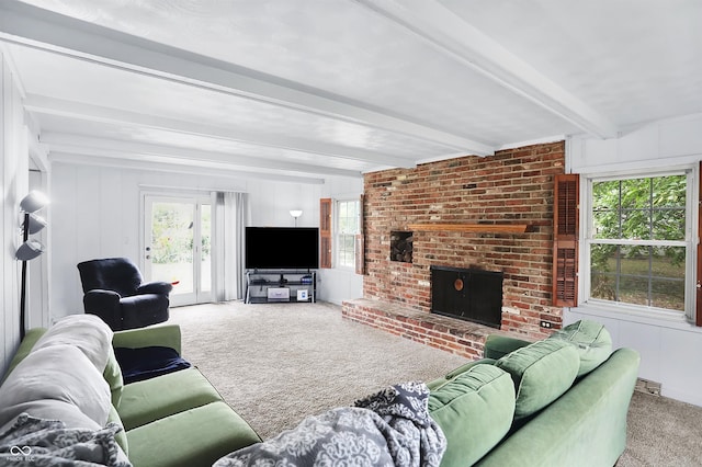 living room featuring a brick fireplace, beamed ceiling, and light colored carpet