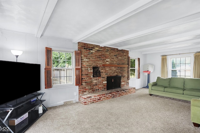 living room with a brick fireplace, beamed ceiling, carpet, and a healthy amount of sunlight