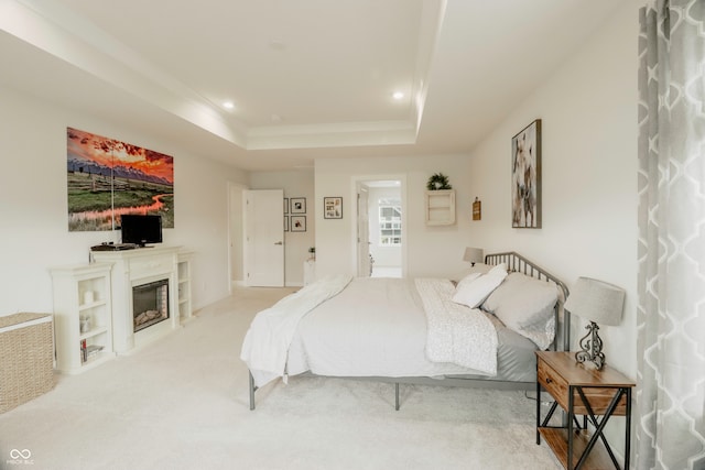 bedroom featuring light carpet and a tray ceiling