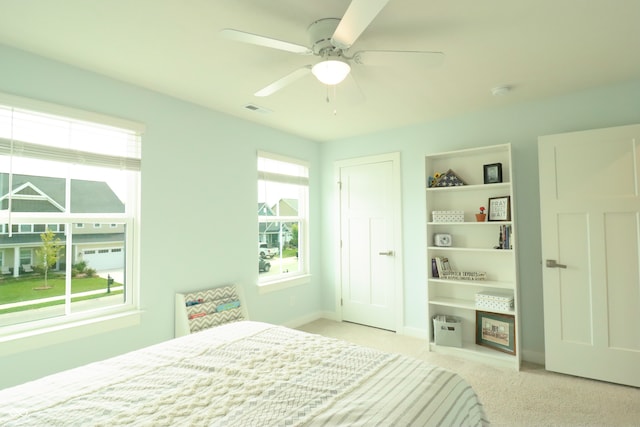 bedroom with multiple windows, ceiling fan, and light colored carpet