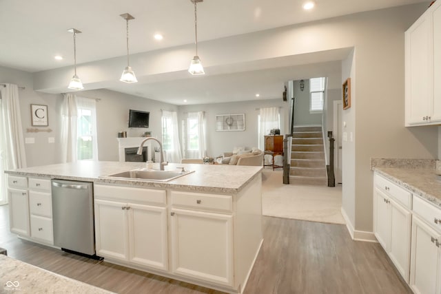 kitchen featuring hanging light fixtures, stainless steel dishwasher, white cabinetry, and sink