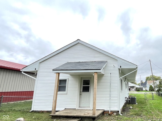 rear view of property with central AC unit and a yard