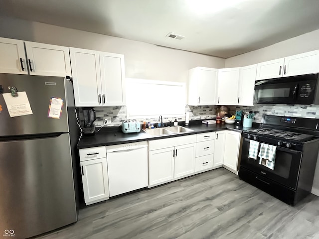 kitchen with light hardwood / wood-style flooring, white cabinetry, tasteful backsplash, and black appliances