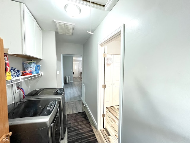 washroom featuring separate washer and dryer, dark hardwood / wood-style floors, and cabinets