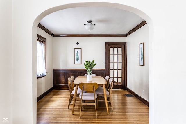 dining area featuring crown molding, wood walls, and hardwood / wood-style flooring