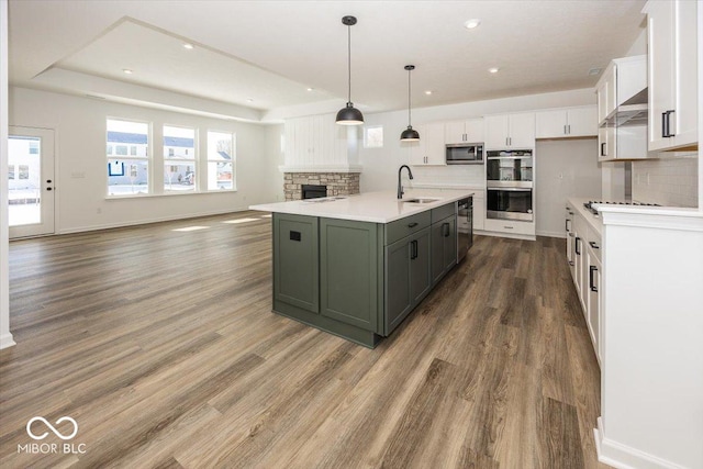 kitchen featuring hanging light fixtures, white cabinetry, a kitchen island with sink, and sink